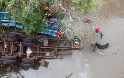 Caminhão cai em rio e bombeiros tentam resgatar motorista