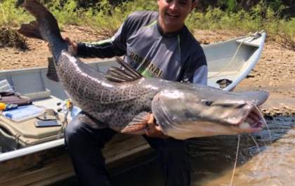 Amigos pescam peixe de aproximadamente 50 quilos