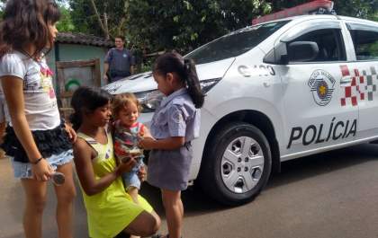 Menina de 4 anos distribui pirulitos de chocolate a crianças carentes com a PM