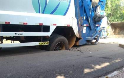 Caminhão da coleta de lixo fica preso em cratera no asfalto