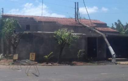 Caminhão se enrosca em fios e derruba poste sobre casa